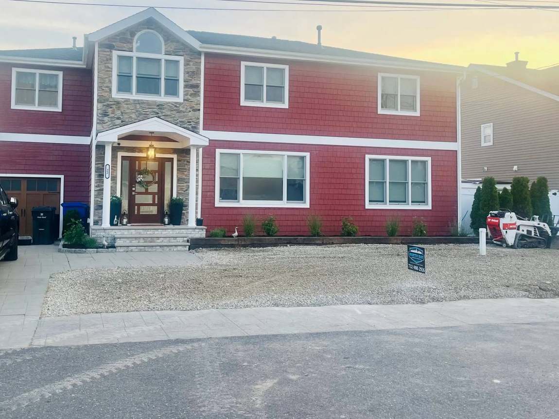 Same front yard after stone garden bed, black steel edging, fresh plantings, and gravel installation